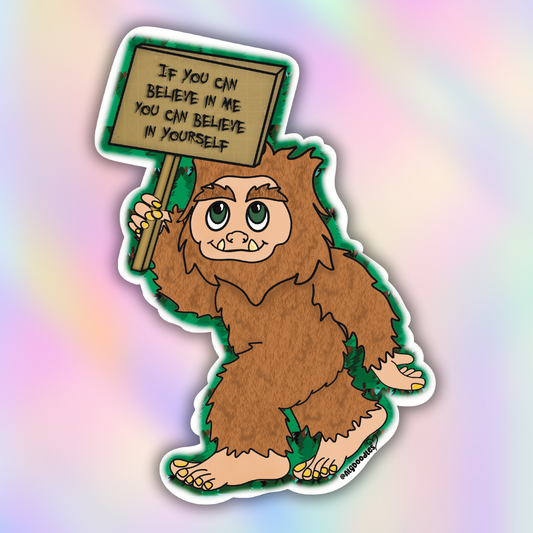 Close-up vinyl sticker of a smiling cartoon Bigfoot holding a motivational sign encouraging self-belief.